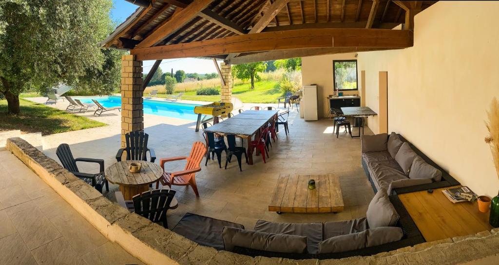 eine Terrasse mit einem Sofa, Tischen und einem Pool in der Unterkunft Les chambres de Lagarrigue, soirée étape in Senouillac