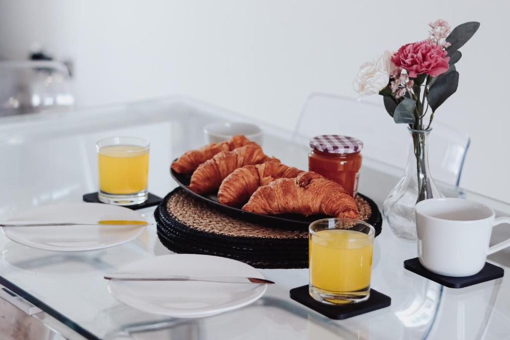 un tavolo con un piatto di prodotti da forno e due bicchieri di succo d'arancia di Greatdown RnR Stays a Greenford