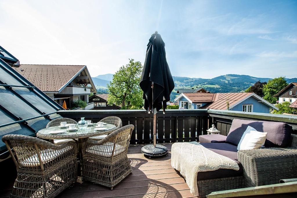 een terras met een tafel, stoelen en een parasol bij Strömbergs Gunnar in Oberstaufen