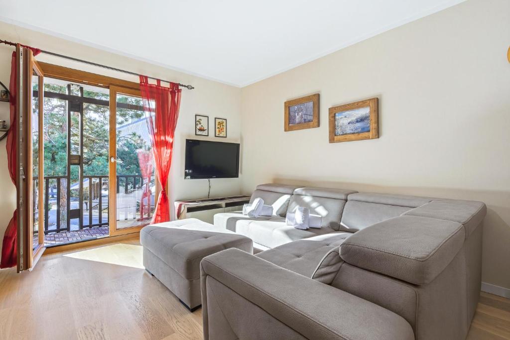 a living room with a couch and a flat screen tv at Hostdomus - La Chapelle in Sauze d'Oulx