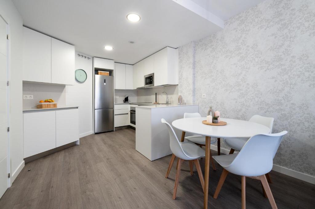 eine Küche mit weißen Schränken und einem Tisch und Stühlen in der Unterkunft Getafe Suites in Getafe