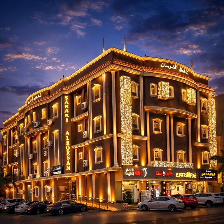 a large building with cars parked in a parking lot at فندق صحارى صبيا - Sahari Sabya Hotel in Şabyā