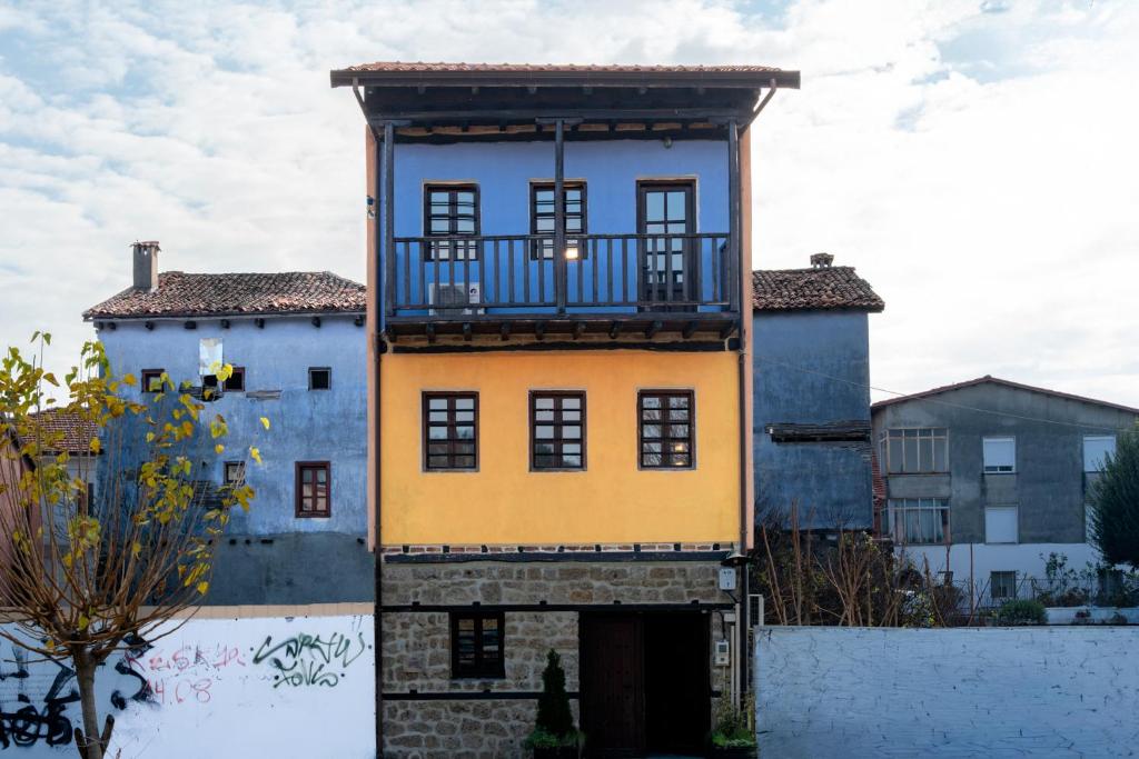 Dieses gelbe und blaue Gebäude verfügt über einen Balkon. in der Unterkunft Αρχοντικό Παπαγιάννη in Edessa