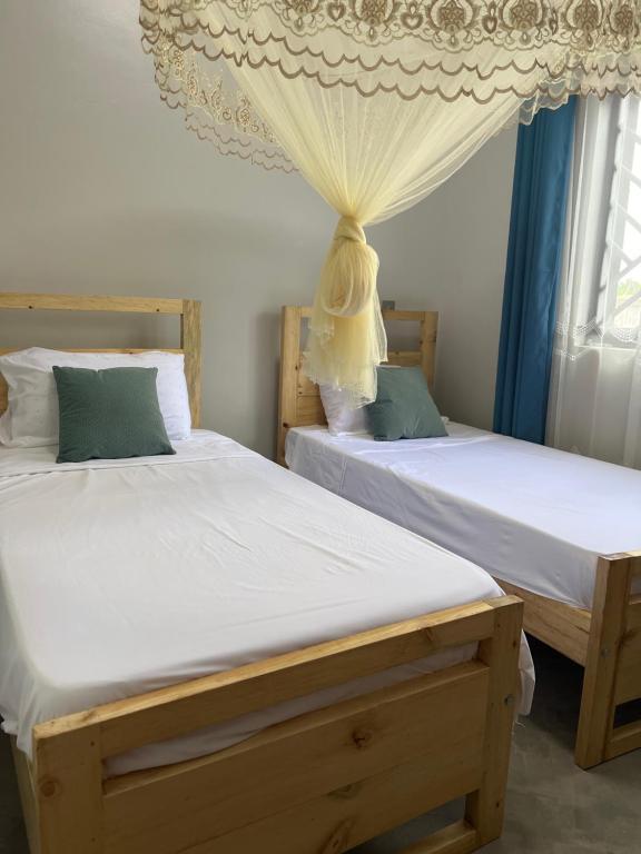 twee bedden naast elkaar in een slaapkamer bij Mufasha Boutique Suites in Kisoro