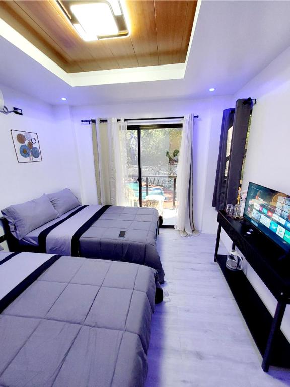a bedroom with two beds and a desk and a television at Buxton Gan Resort Hotel in San Andres