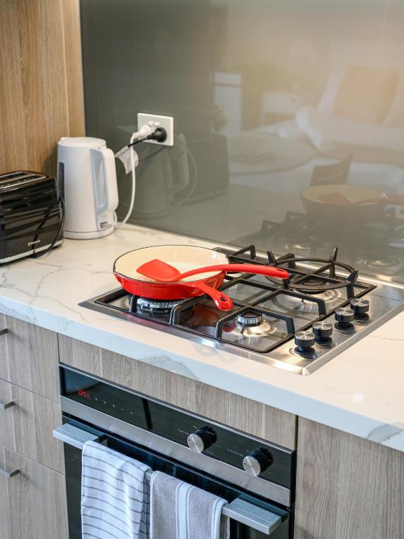 a red pan sitting on top of a stove in a kitchen at Tranquil Studio in Schofields in Schofields