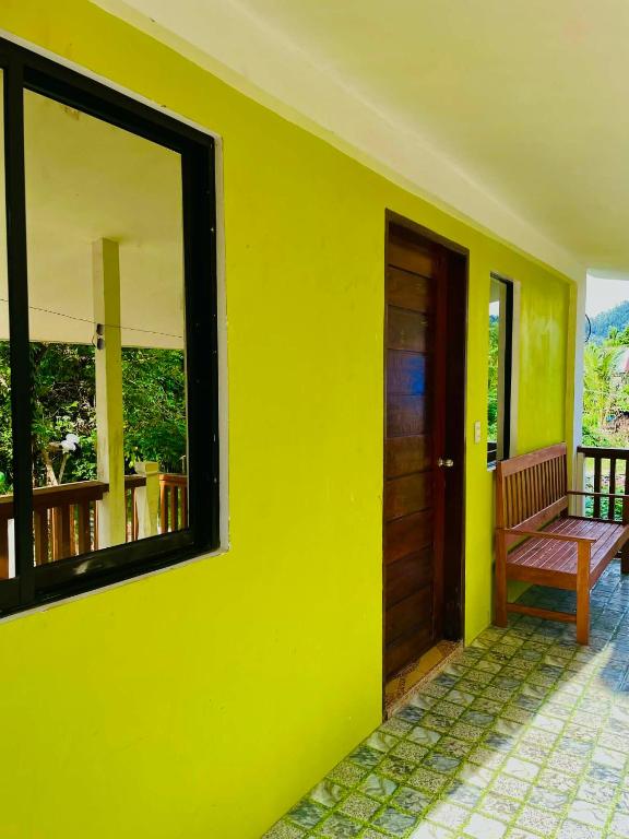 a yellow wall with a door and a bench on a balcony at Kenji Guest House in San Vicente