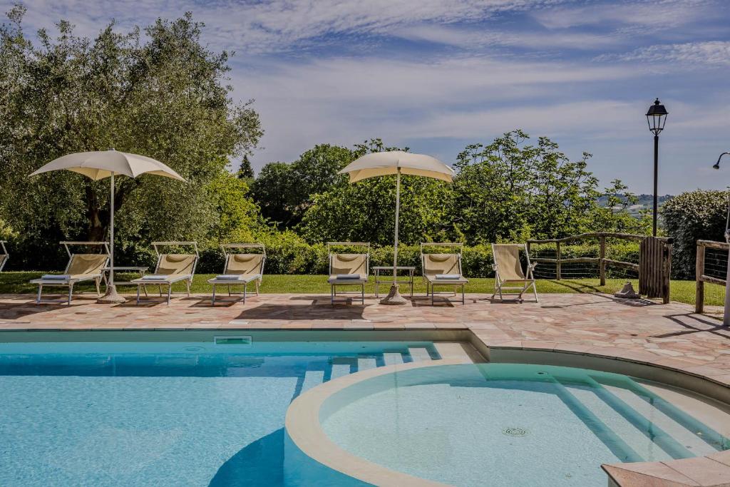 une piscine avec chaises et parasols dans l'établissement Agriturismo Villa Beatrice, à Mondavio