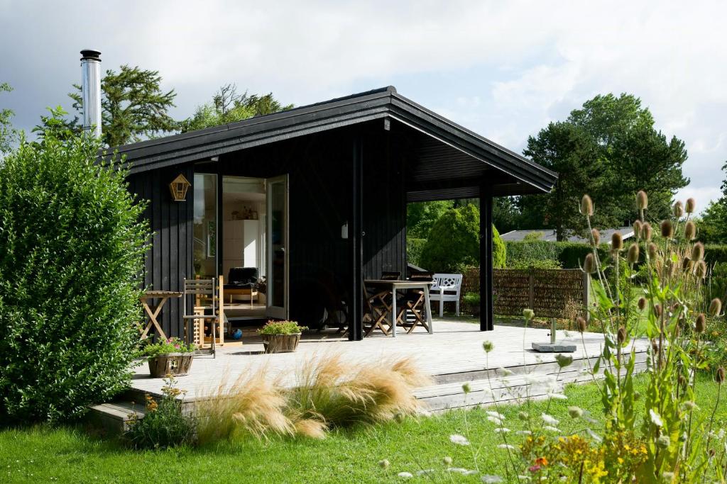 un capanno nero con un ponte in un giardino di Summer Bliss With Vibrant Garden In Nødebohuse a Kikhavn