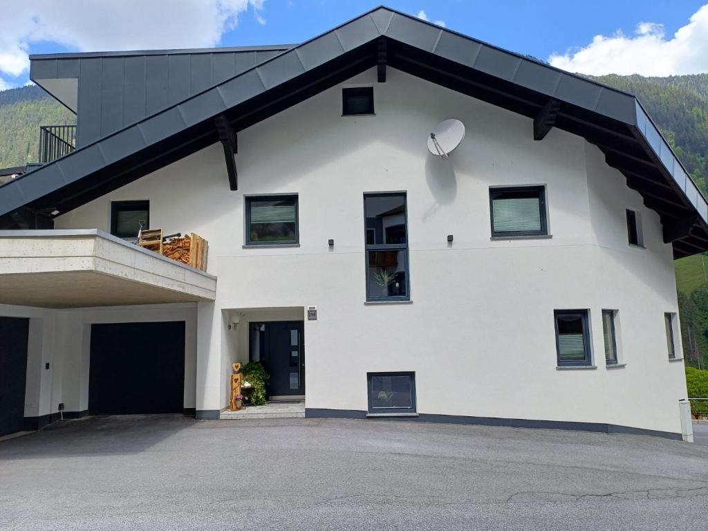 une maison blanche avec un toit noir dans l'établissement Haus Dominik, à See
