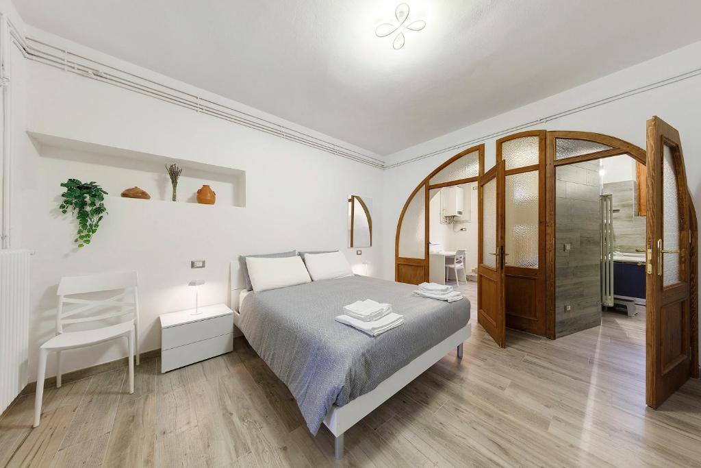 een witte slaapkamer met een bed en een stoel bij In Casetta da Mae in Lorenzago