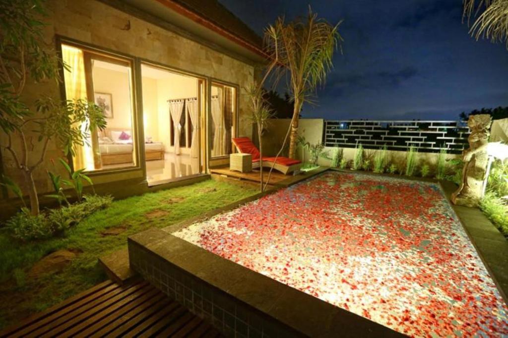 a backyard with a large pool with a red chair at Asri Sari Ubud Resort in Ubud