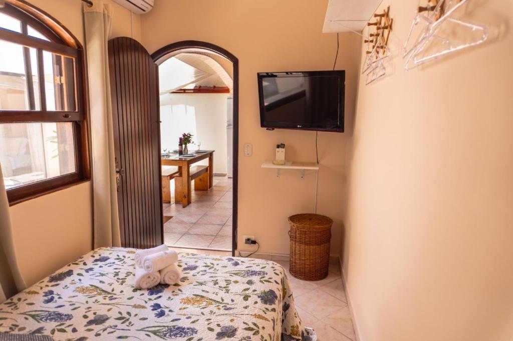 een slaapkamer met een bed en een tv aan de muur bij Recanto aconchego in Peruíbe