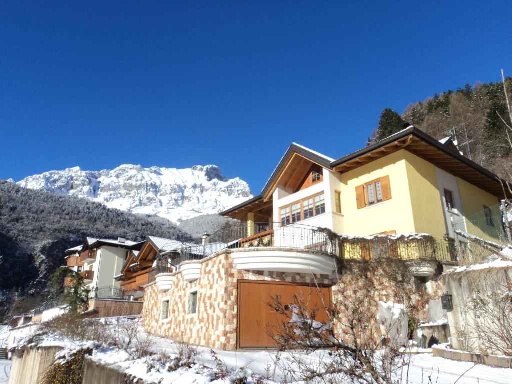 une maison dans la neige avec des montagnes en arrière-plan dans l'établissement Villa Gardenia Molveno, à Molveno