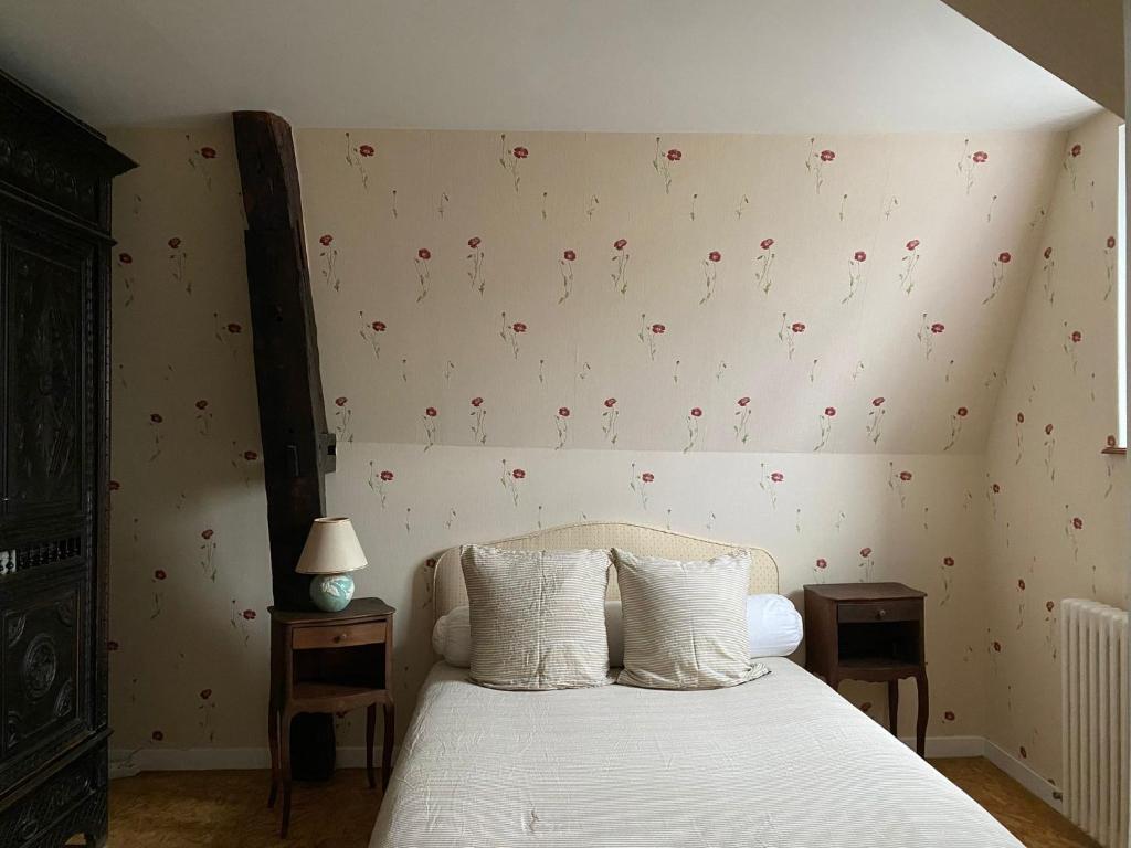 een slaapkamer met een wit bed met rode bloemen aan de muur bij Le rêve de Jocelyne - Grande maison au Neubourg in Le Neubourg