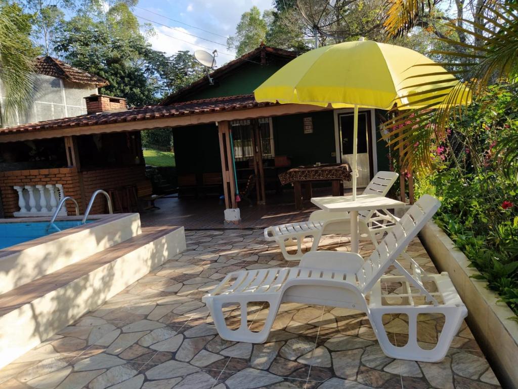 een terras met een tafel, stoelen en een parasol bij Sítio Refúgio Primavera in Monte Verde