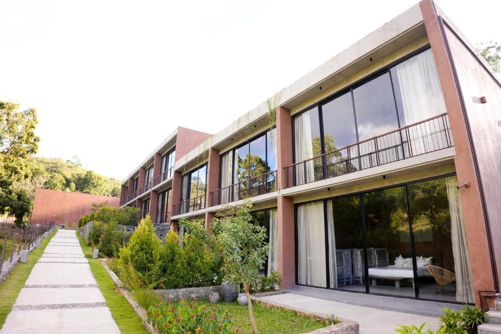 a building with large glass windows and a sidewalk at Ayana Villa By KPM in Varagampadi