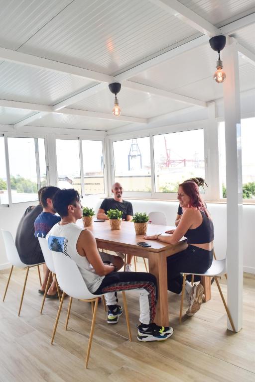 a group of people sitting at a table in a room at La Isleta Nest Hostel in Las Palmas de Gran Canaria