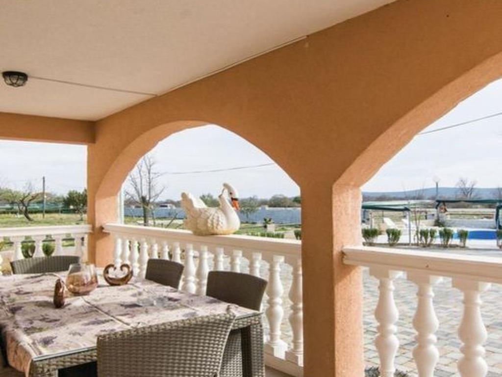 a porch with a table and chickens on the balcony at Apartment Laura mit Pool by Interhome in Stankovci