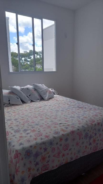 a bedroom with a bed with a flowered blanket and windows at Apartamento LITORAL NORTE in Abrantes
