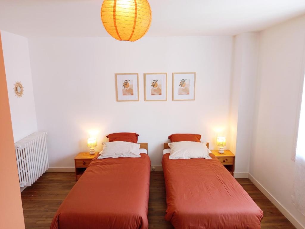 twee bedden in een kleine kamer met twee lampen bij Porh tramesse in Saint-Thuriau