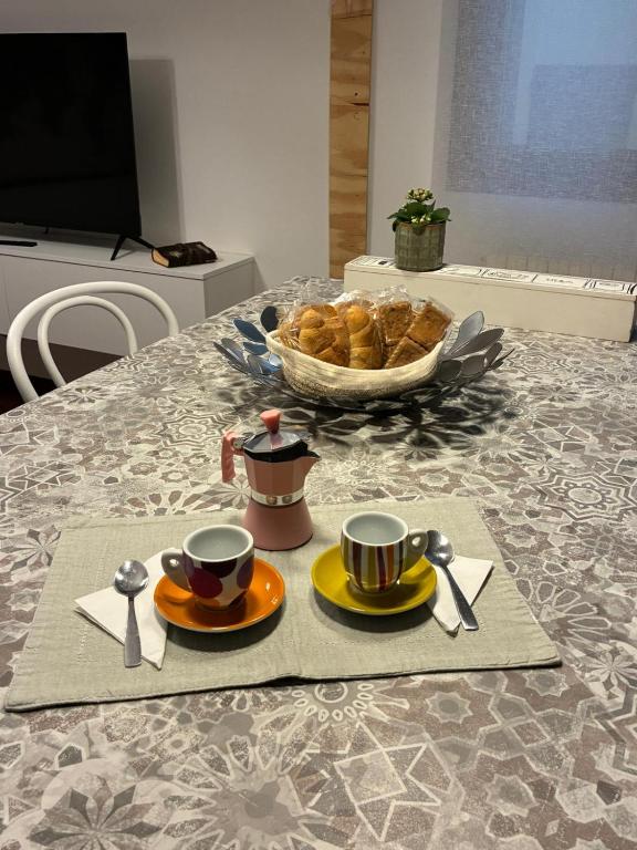 een tafel met twee kopjes en een kom brood bij H2O Home2Office in Budrio
