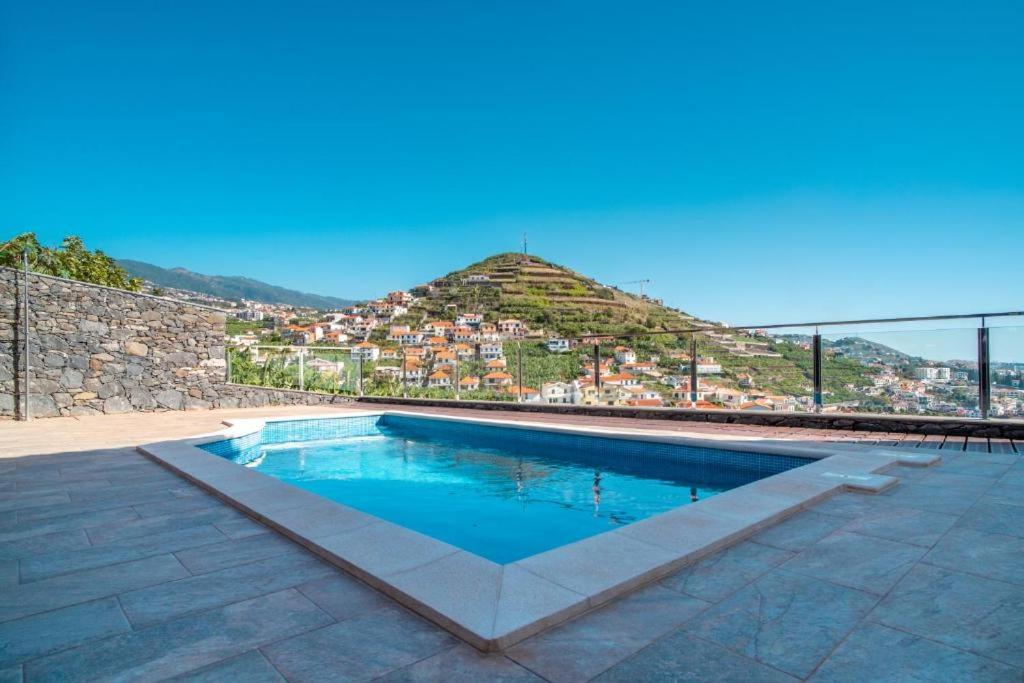 een zwembad met een heuvel op de achtergrond bij Camara De Lobos Lux Villa in Câmara de Lobos