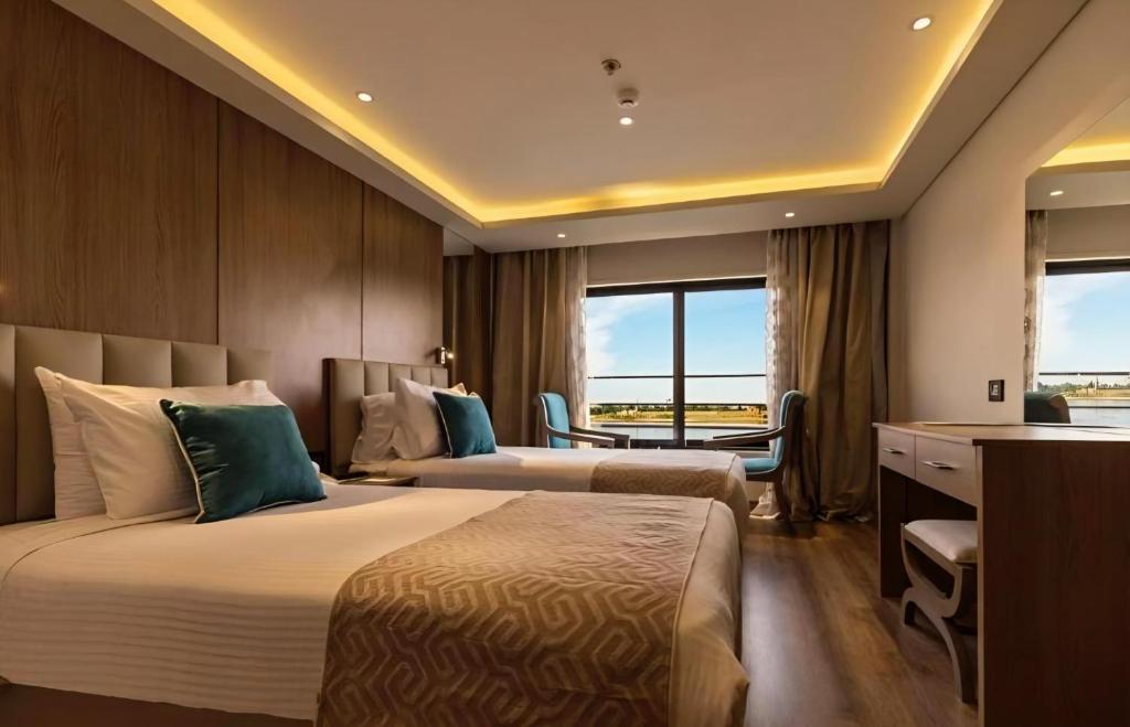 Una habitación de hotel con dos camas y un escritorio. en Nile cruise from Luxor to Aswan 4 nights From Aswan to Luxor 3 nights, en Luxor