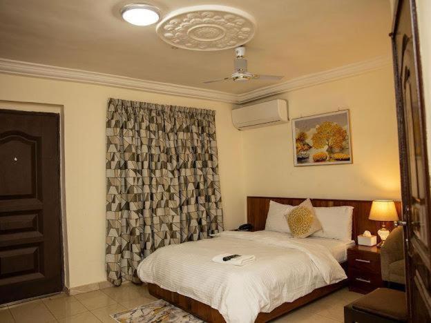 een slaapkamer met een bed en een raam met een gordijn bij Selwilliam Hotel Limited in Trofwi