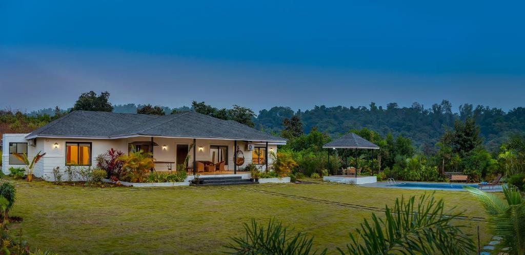 a house with a large yard and a pool at SaffronStays Green Lawns in Pāli