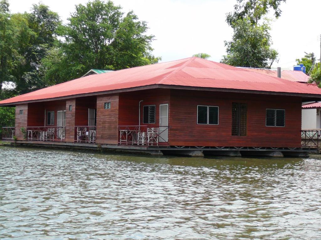 a red and white boat sitting on top of a body of water at VN Guesthouse in Kanchanaburi City