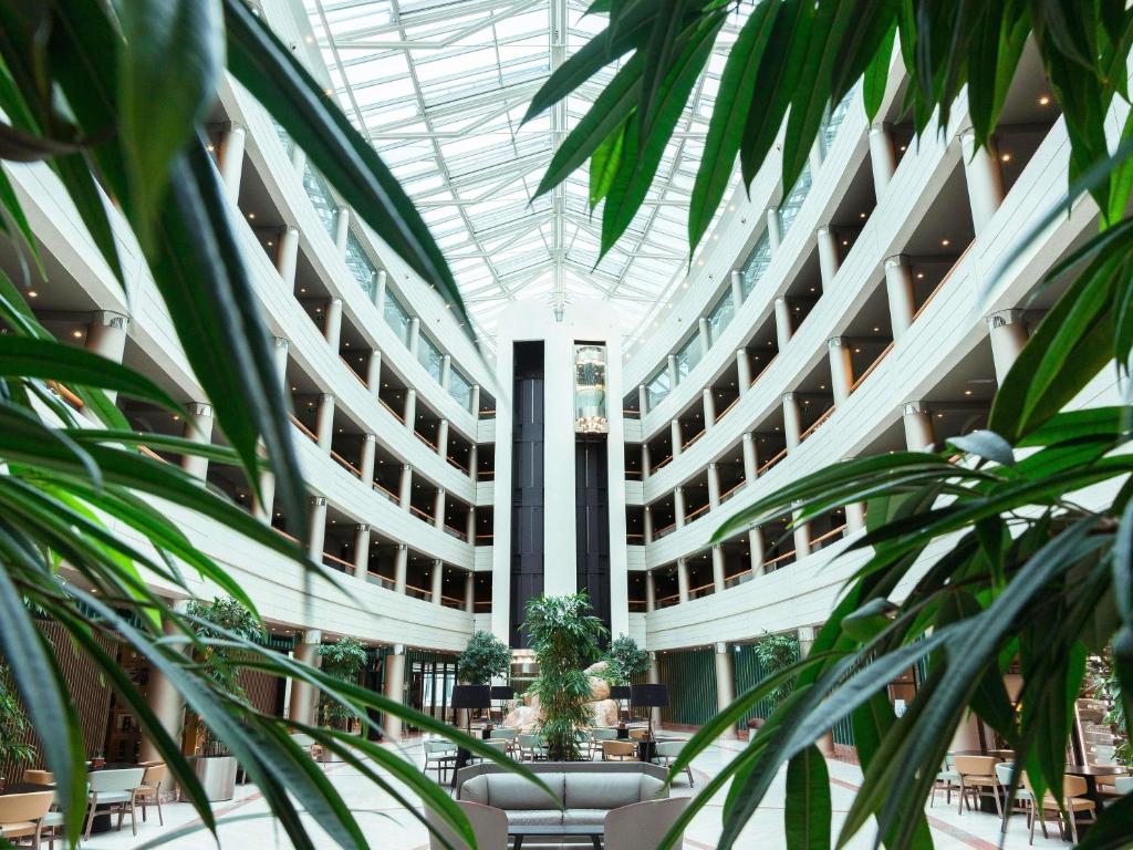 een arium van een gebouw met tafels en stoelen bij Sofitel Luxembourg Europe in Luxemburg