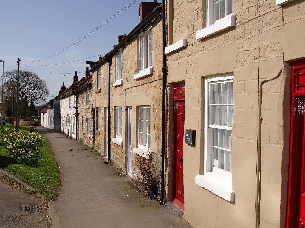 a row of houses with red doors on a street at Beacon Cottage in Pickering