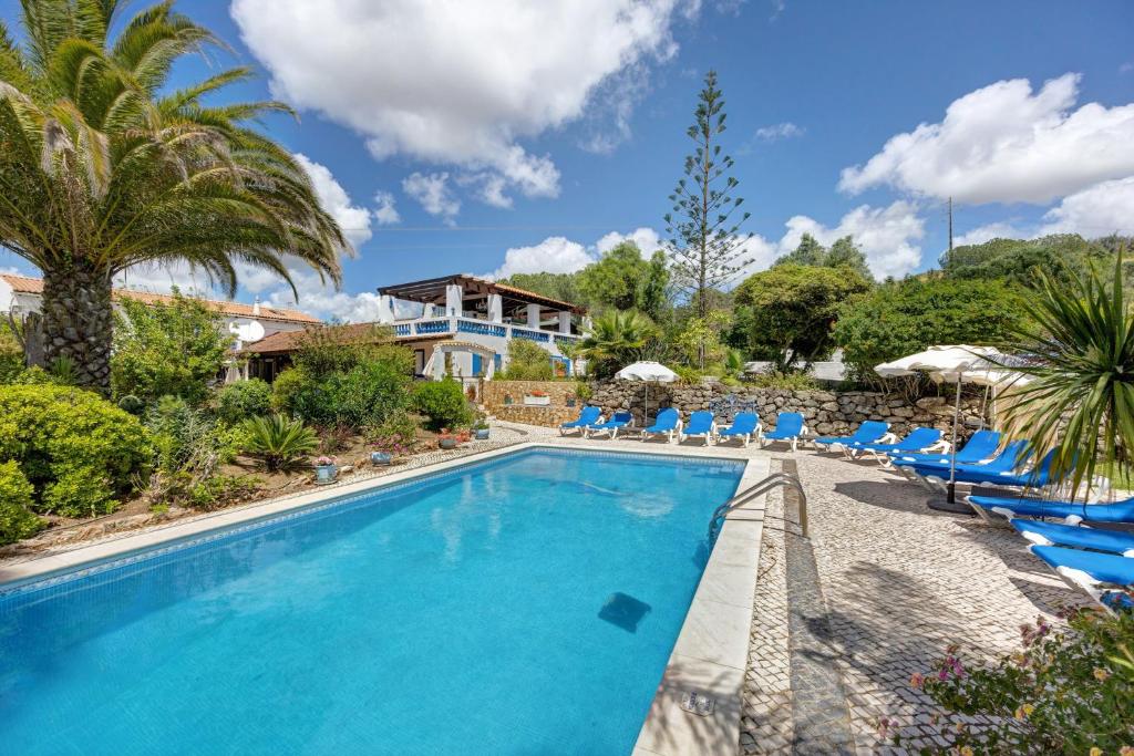 una piscina con sedie e una casa di Quinta das Achadas - Quartos a Cerro Ruivo