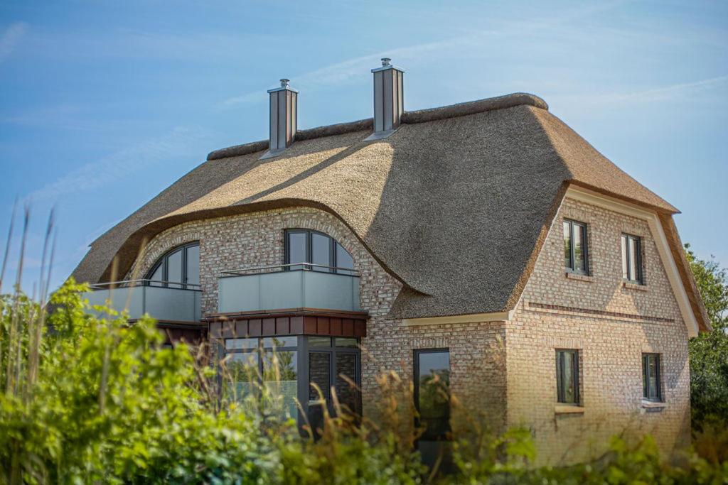 a large brick house with a gambrel roof at De Bööi - Luxus-Haus mit Meerblick, Sauna & Kamin in Fehmarn