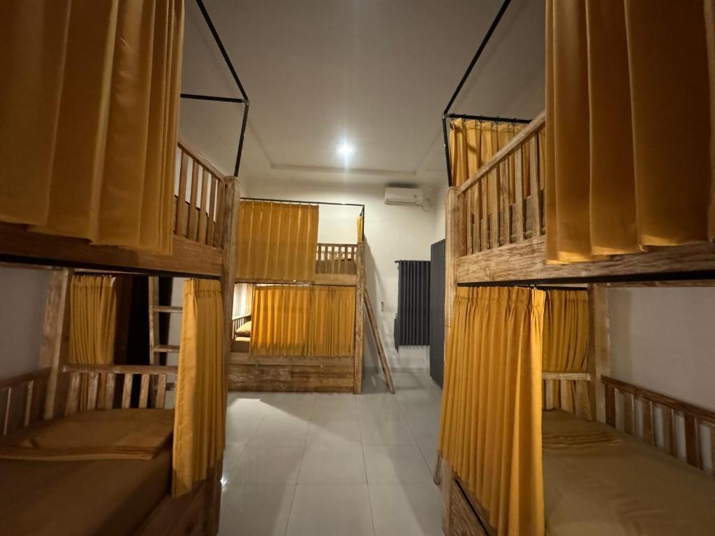 Zimmer mit mehreren Etagenbetten und gelben Vorhängen in der Unterkunft Dream Beach Hostel Lembongan in Nusa Lembongan