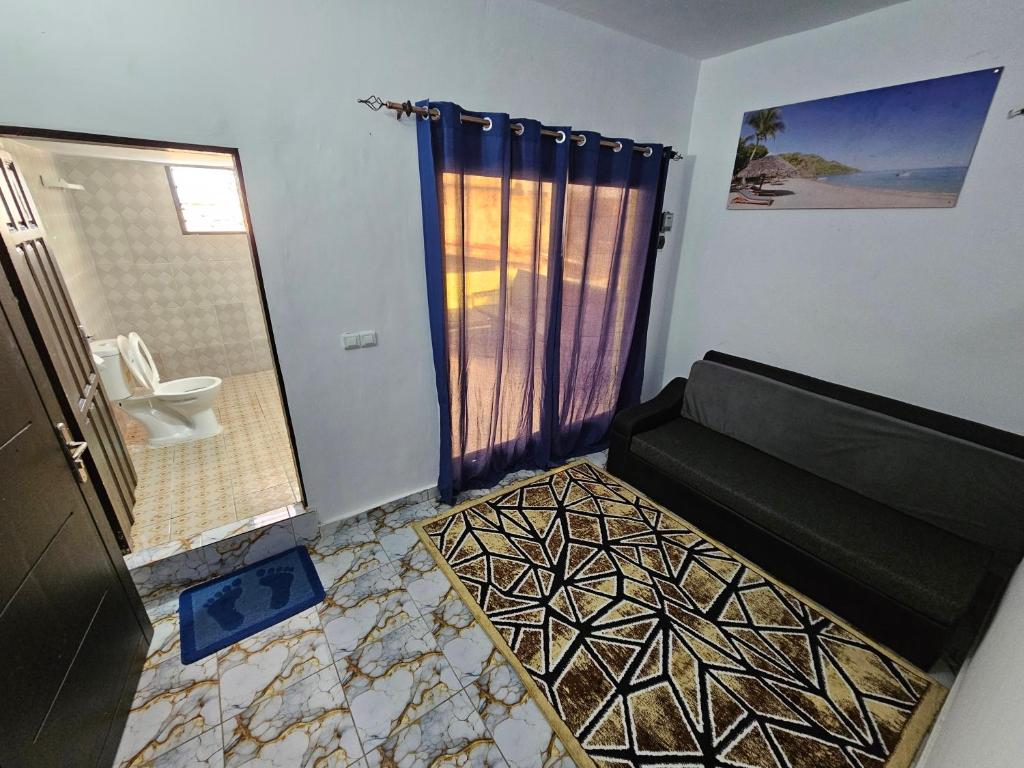 a living room with a couch and a shower at appartement avec balcon à Port Bouet cité SiPiM aéroport in Abidjan