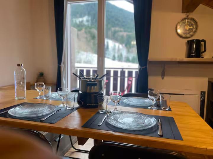 a wooden table with plates and wine glasses on it at Studio Belle Neige in Bernex