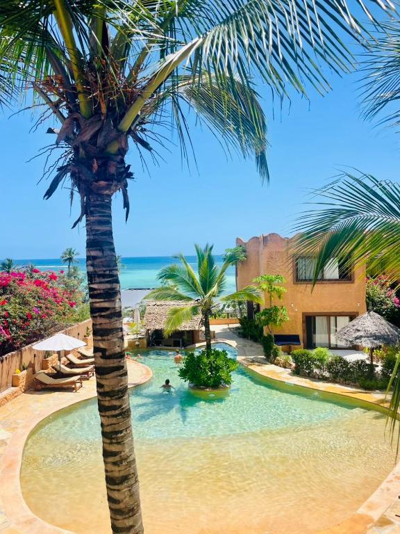 a palm tree in a swimming pool next to a resort at Di Milo Boutique Hotel in Kiwengwa