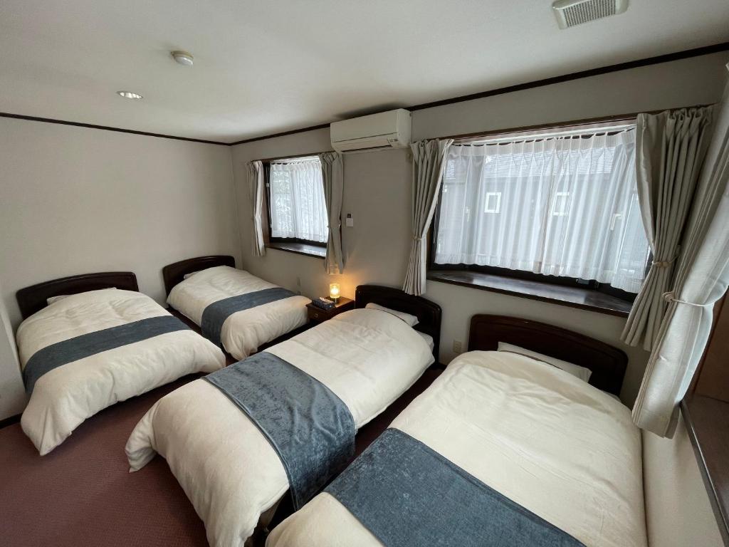 una camera con quattro letti e due finestre di ペンション歩野慕野-honobono a Kitashiobara