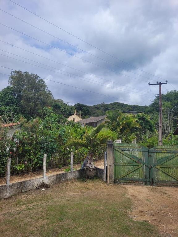 un cancello verde davanti a un campo con alberi di Sítio Guanabara a Guaramiranga