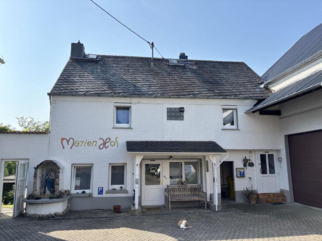 een wit huis met een hond er voor bij Ferienwohnung Marienhof OG in Seelbach