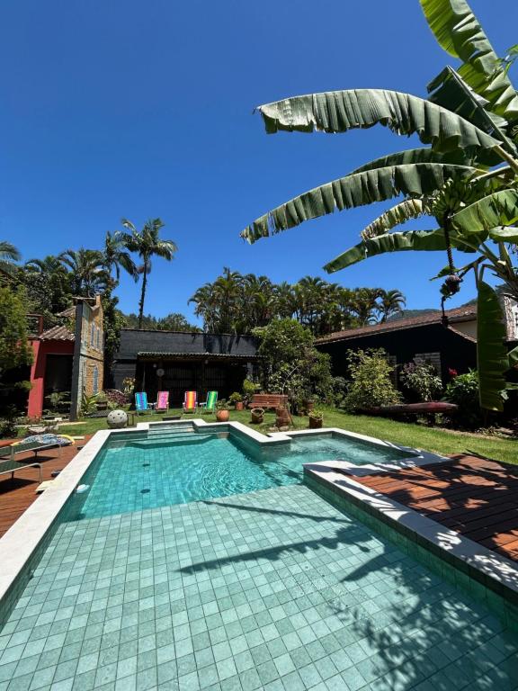 una piscina in una villa con una palma di Pousada Preamare a Ubatuba