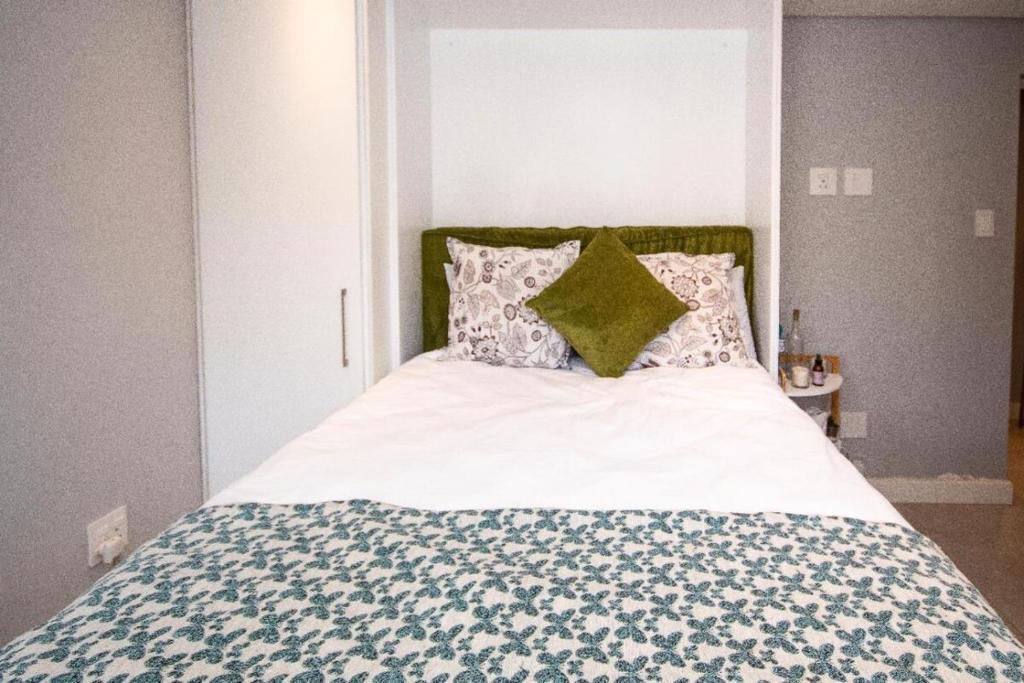 een bed met een blauwe en witte deken en kussens bij SeaPoint MicroStudio - Walk 2 Promenade&Waterfront in Kaapstad