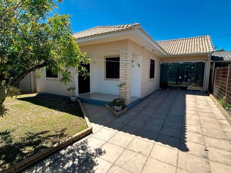 een klein wit huis met een patio in een tuin bij Casa aconchegante perto do mar em Imbé in Imbé