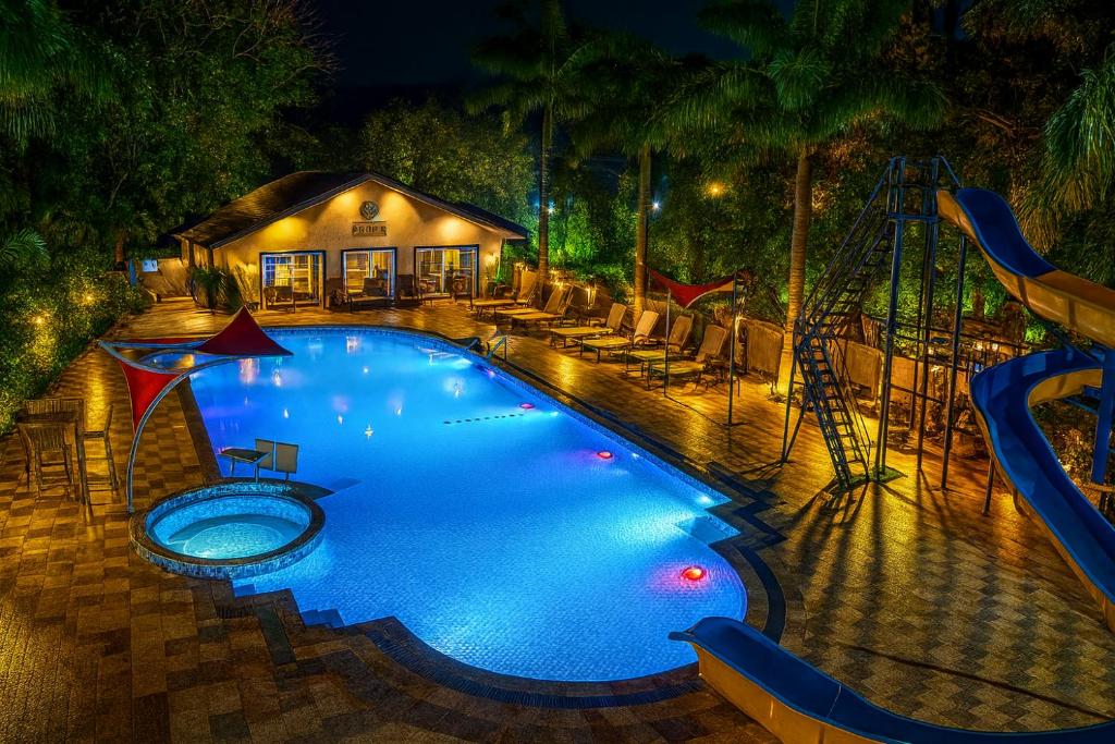 ein Schwimmbad in der Nacht mit Rutsche in der Unterkunft Basilica Resort - Where Luxury Redefines in Mahabaleshwar