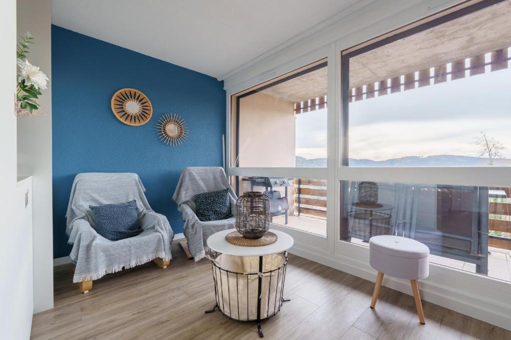 un salon avec deux chaises et une grande fenêtre dans l'établissement La Résidence Le Belvédère - Avec Balcon, à Le Tholy
