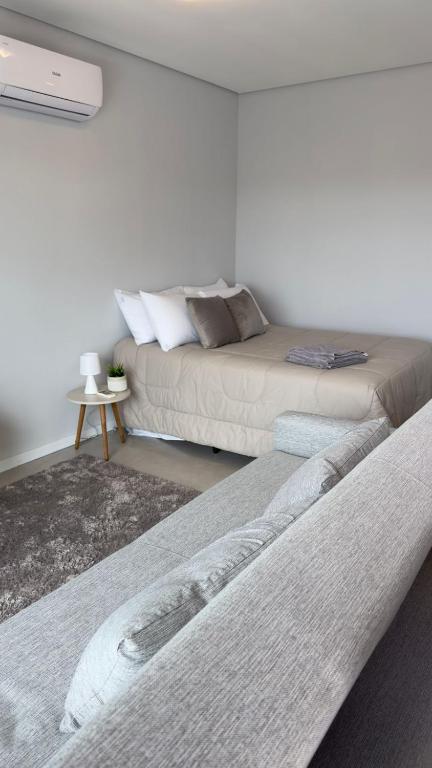 two beds and a couch in a room at Loft Central com garagem in Pelotas
