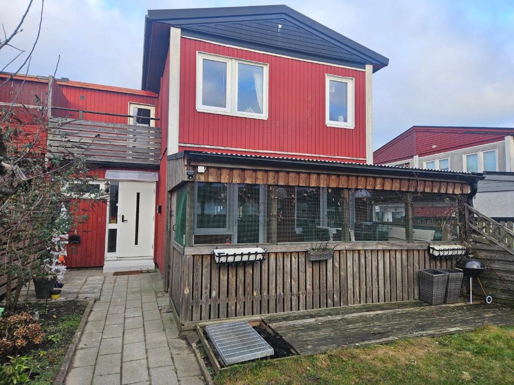 a red house with a wooden fence in a yard at Malmoxie Unic Garden House in Oxie