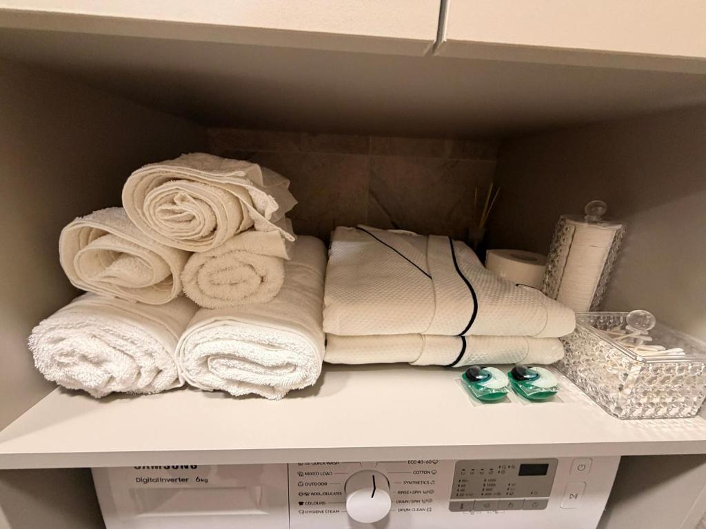 een stapel handdoeken op een plank bij Ūla Apartments in Mažeikiai